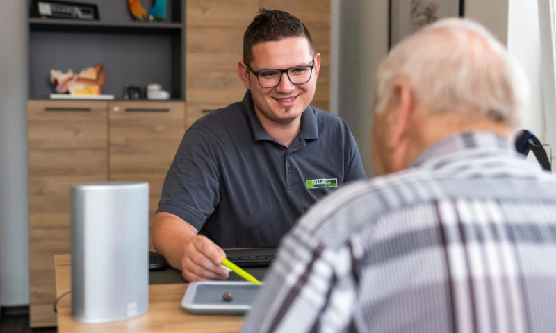 Junger Berater erklärt älterem Mann freundlich Finanzthemen im modernen Büro.