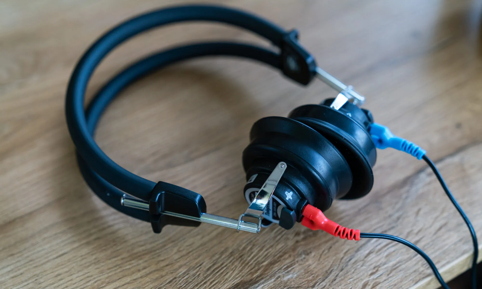 Schwarzer Studiokopfhörer mit Kabeln auf Holztisch, Musik- und Audio-Equipment.